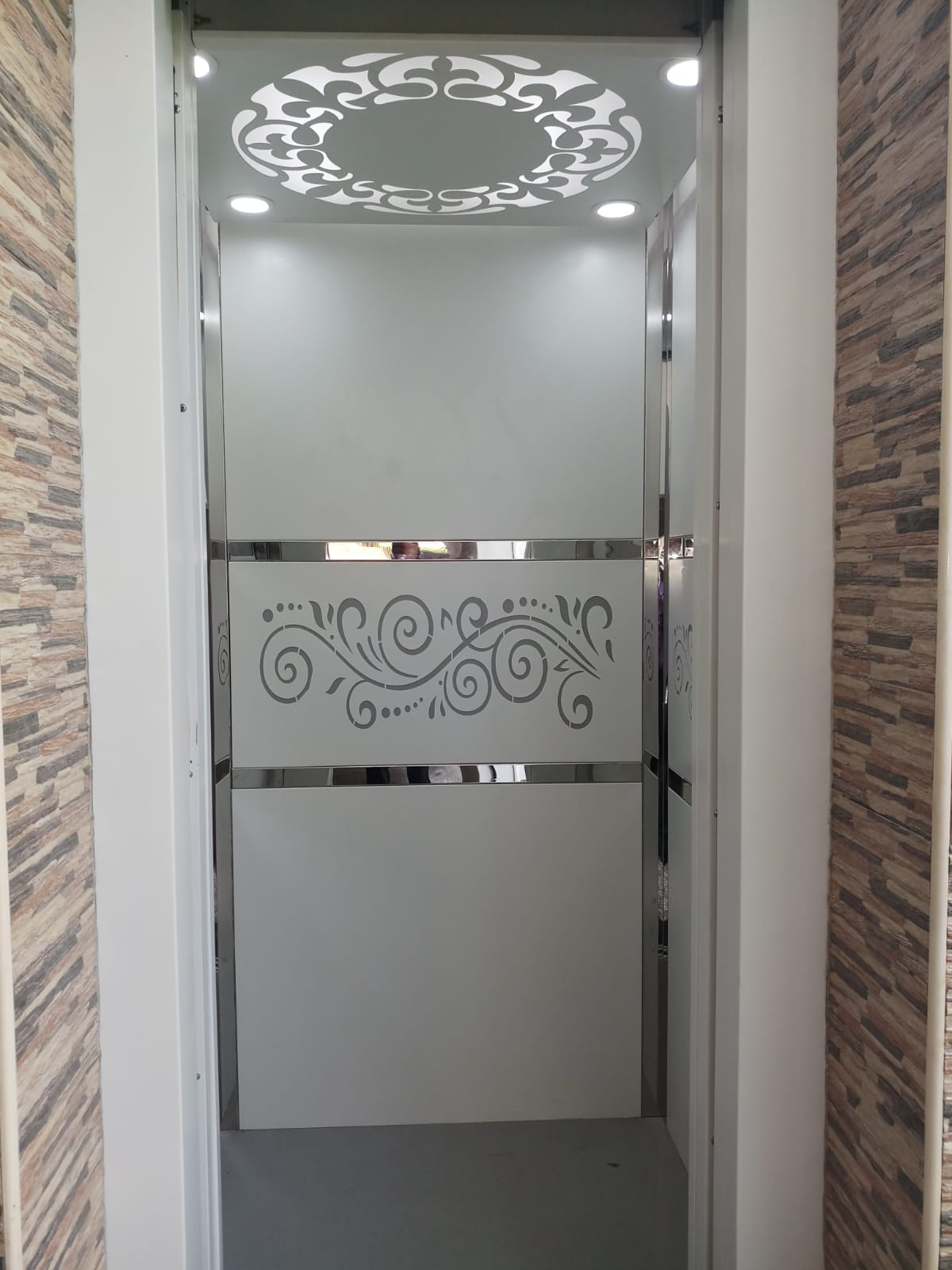 Home elevator cabin with decorative ceiling and etched panels